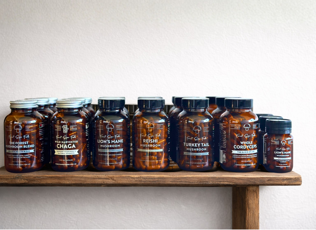 Row of amber glass jars containing various mushroom supplement capsules on a wooden shelf against white wall